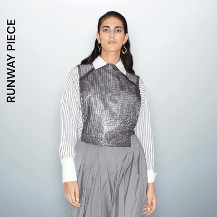 Model  wearing a metallic silver sleeveless crop top with a shimmering texture, crafted from polyester, designed by Unfolloworld.

