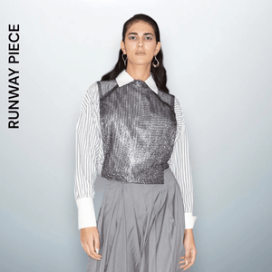 Model  wearing a metallic silver sleeveless crop top with a shimmering texture, crafted from polyester, designed by Unfolloworld.

