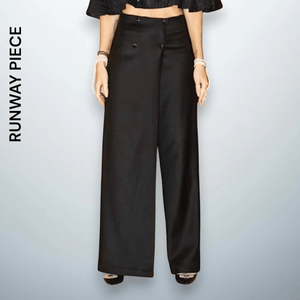 Model wearing high-waist wide-leg black trousers with button detail on the waistband, crafted from 100% wool, a luxury piece by Unfolloworld.

